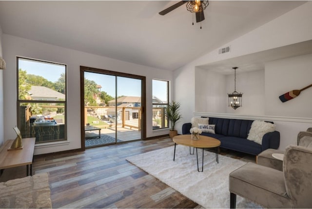 living room with hardwood / wood-style floors, ceiling fan with notable chandelier, and vaulted ceiling