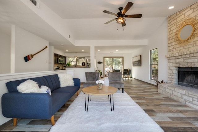 living room with ceiling fan, wood-type flooring, and a brick fireplace