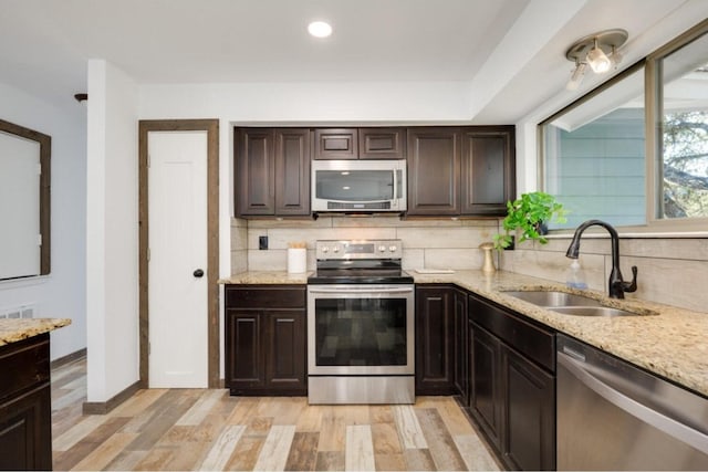 kitchen featuring sink, tasteful backsplash, light hardwood / wood-style floors, dark brown cabinets, and appliances with stainless steel finishes