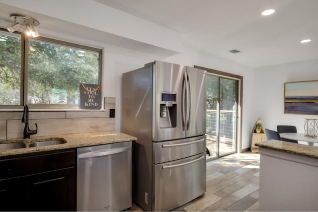 kitchen featuring sink, stainless steel appliances, light stone counters, plenty of natural light, and light wood-type flooring