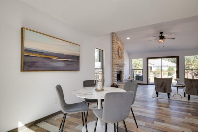 dining area featuring ceiling fan, a fireplace, wood-type flooring, and vaulted ceiling