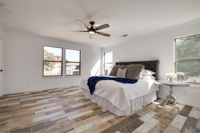 bedroom with ceiling fan, light wood-type flooring, and crown molding