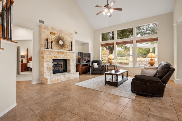 living room featuring ceiling fan, light tile patterned flooring, a stone fireplace, and high vaulted ceiling