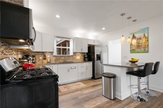 kitchen featuring light wood-type flooring, pendant lighting, tasteful backsplash, and stainless steel appliances