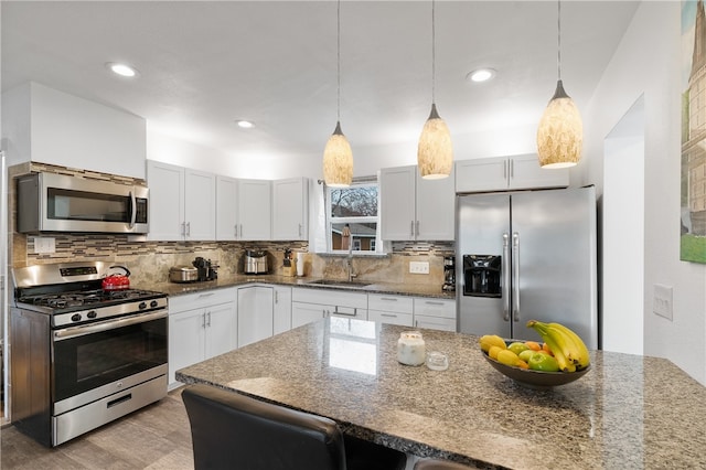 kitchen with dark stone countertops, stainless steel appliances, a kitchen breakfast bar, sink, and decorative backsplash