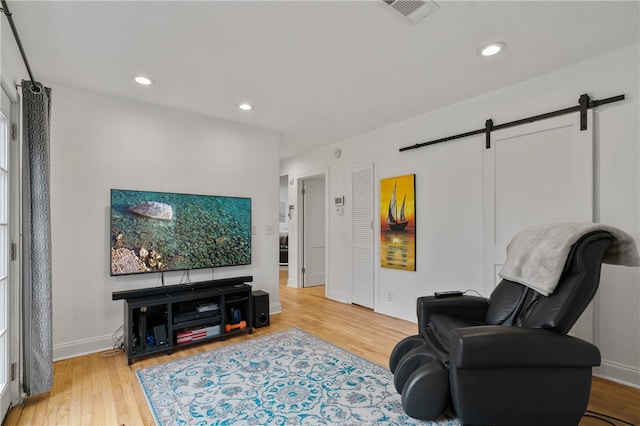 living area with a barn door and light wood-type flooring