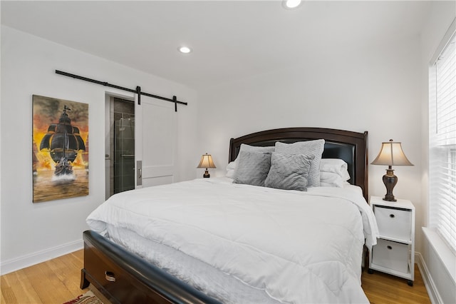 bedroom with light hardwood / wood-style flooring and a barn door