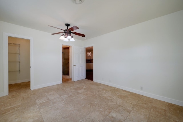 unfurnished bedroom featuring a walk in closet, a closet, ceiling fan, and light tile floors