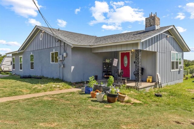 222 Pope Bnd N, Cedar Creek, TX 78612 - view of front of home with a shingled roof, board and batten siding, a front yard, and a chimney