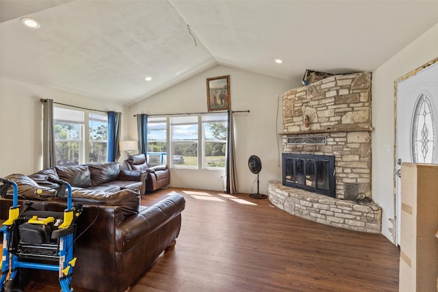 living room with hardwood / wood-style flooring, a stone fireplace, vaulted ceiling, and a wealth of natural light