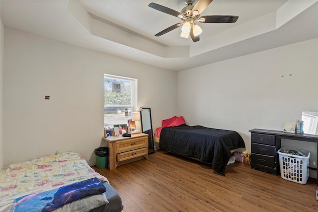 bedroom with a tray ceiling, ceiling fan, and hardwood / wood-style flooring