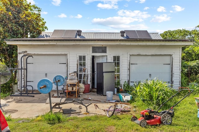 garage with stainless steel refrigerator and solar panels