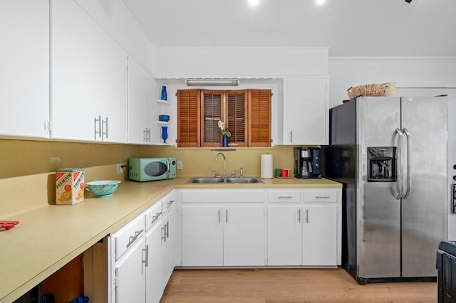 kitchen featuring light wood-type flooring, stainless steel fridge, sink, and white cabinets