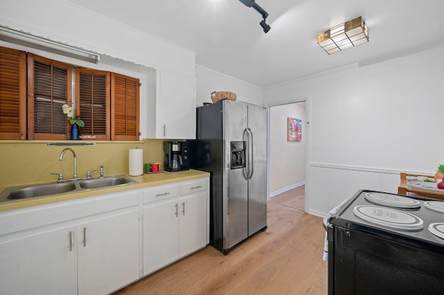 kitchen featuring sink, stainless steel fridge, black range with electric cooktop, and white cabinets