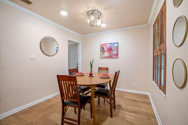 dining space with crown molding, light hardwood / wood-style floors, and a chandelier