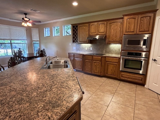 kitchen with appliances with stainless steel finishes, tasteful backsplash, ornamental molding, sink, and light tile patterned floors