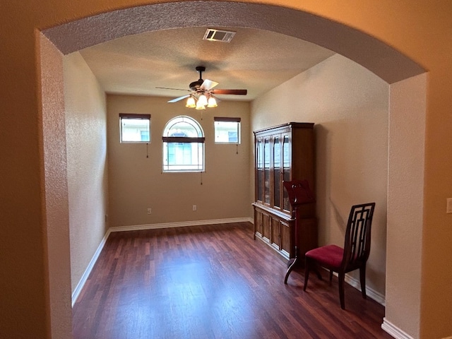 foyer entrance with a textured ceiling, ceiling fan, and dark wood-type flooring