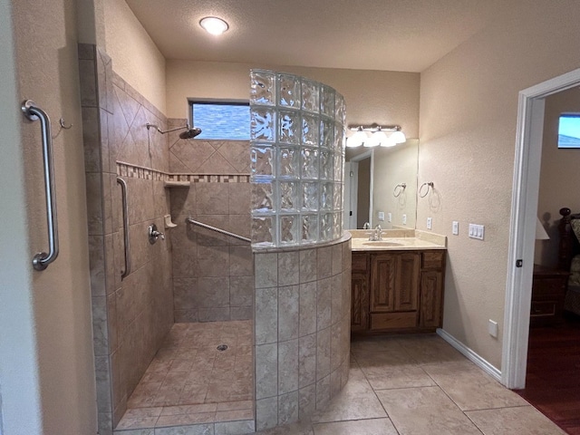 bathroom featuring tiled shower, vanity, and tile patterned flooring