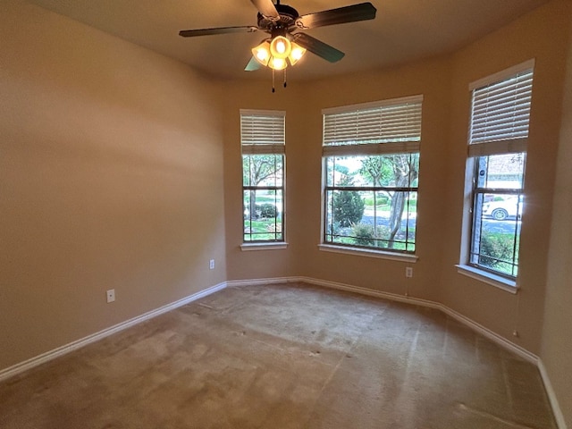 empty room featuring ceiling fan, a healthy amount of sunlight, and light carpet