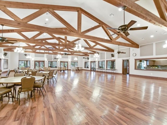 dining space with beamed ceiling, ceiling fan with notable chandelier, light hardwood / wood-style floors, and high vaulted ceiling