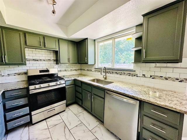 kitchen featuring green cabinets, backsplash, appliances with stainless steel finishes, sink, and a textured ceiling