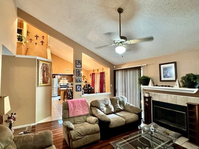 living room featuring light tile patterned flooring, vaulted ceiling, ceiling fan, and a textured ceiling