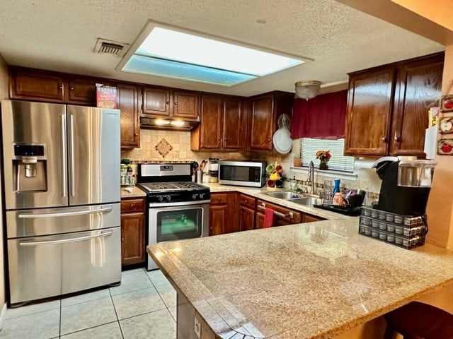 kitchen featuring light tile patterned floors, sink, stainless steel appliances, and kitchen peninsula