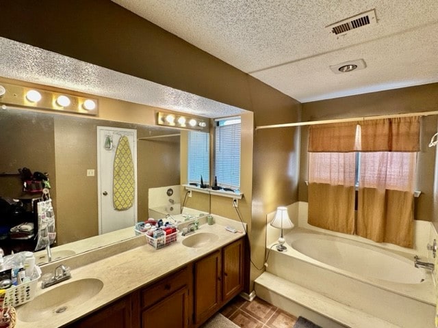 bathroom featuring a textured ceiling, a bath, double sink vanity, and tile patterned floors