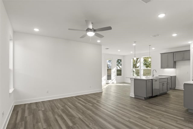 kitchen with gray cabinetry, decorative light fixtures, a center island with sink, white dishwasher, and dark hardwood / wood-style floors