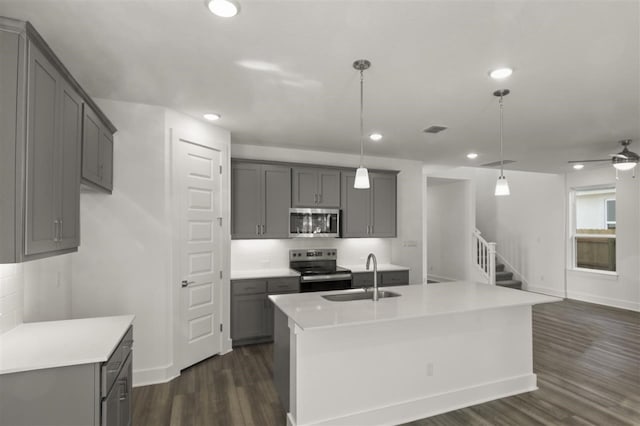 kitchen with an island with sink, stainless steel appliances, sink, and gray cabinetry