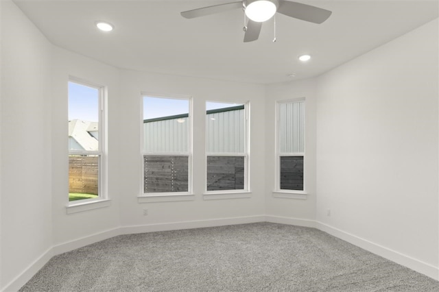 carpeted spare room featuring ceiling fan and plenty of natural light