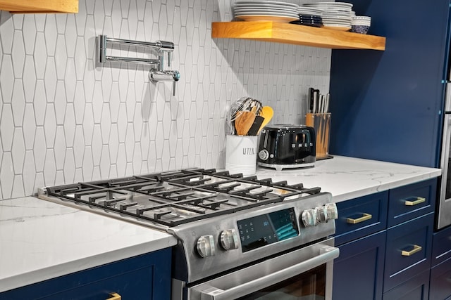 kitchen featuring blue cabinetry, light stone countertops, stainless steel gas stove, and backsplash