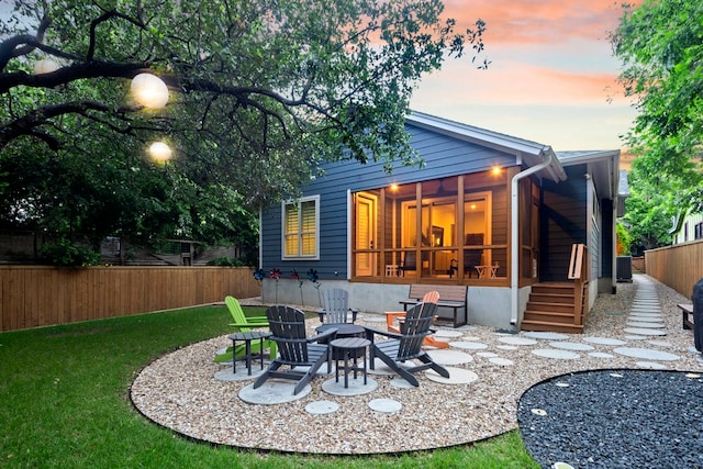 back house at dusk with a fire pit, a yard, and a patio area