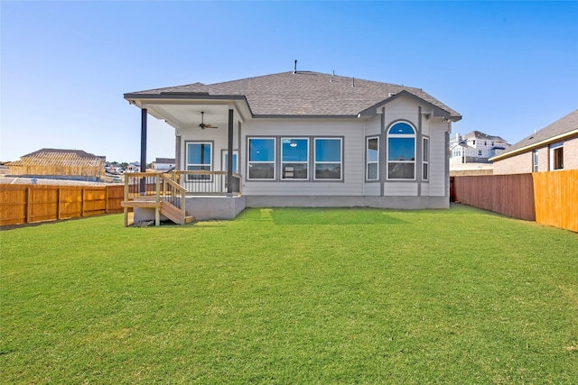 back of house with ceiling fan and a yard