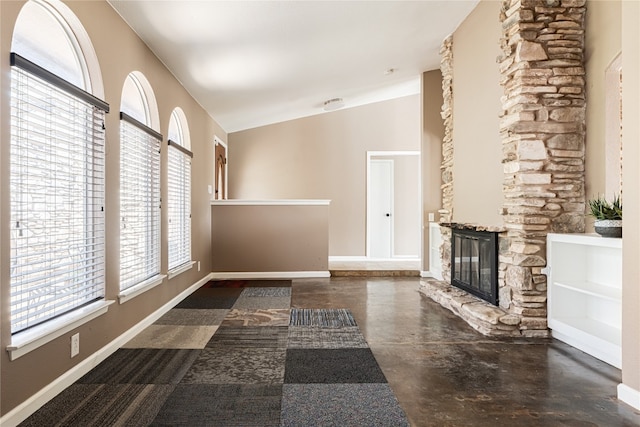 unfurnished living room featuring a stone fireplace and lofted ceiling