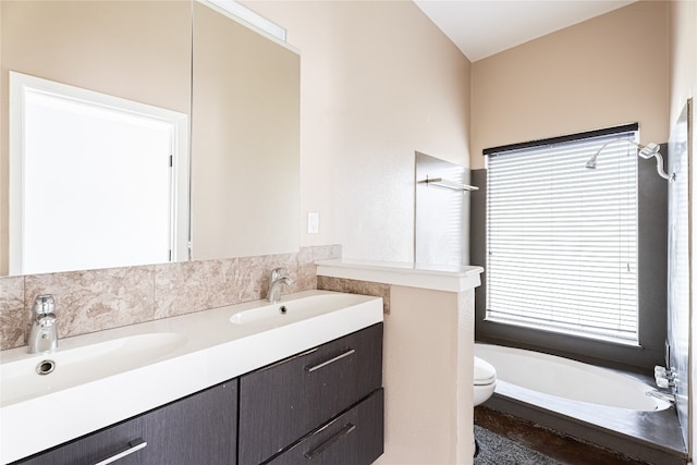 bathroom featuring dual sinks, a bathtub, toilet, and large vanity