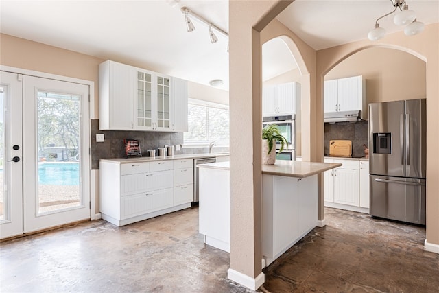 kitchen featuring a healthy amount of sunlight, tasteful backsplash, rail lighting, and stainless steel appliances