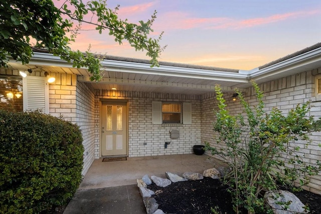 exterior entry at dusk featuring brick siding