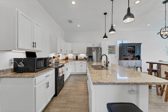 kitchen with black appliances, sink, a kitchen island with sink, and hanging light fixtures