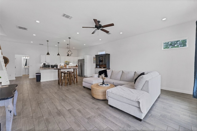 living room featuring light wood-type flooring and ceiling fan