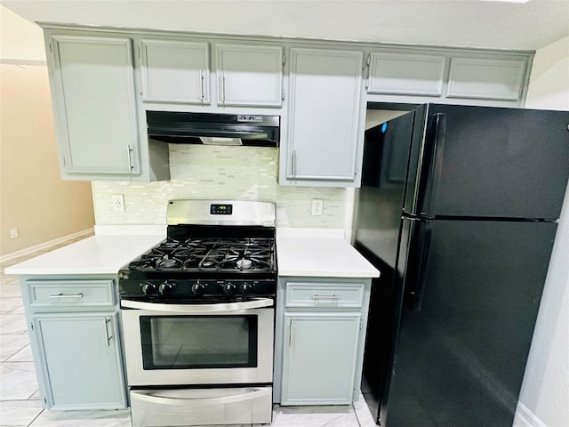 kitchen with light tile patterned flooring, gas stove, tasteful backsplash, black refrigerator, and extractor fan