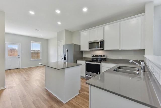 kitchen featuring light wood-type flooring, white cabinetry, stainless steel appliances, and a sink