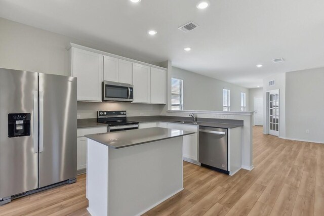 kitchen with stainless steel appliances, visible vents, light wood-style flooring, white cabinets, and a sink