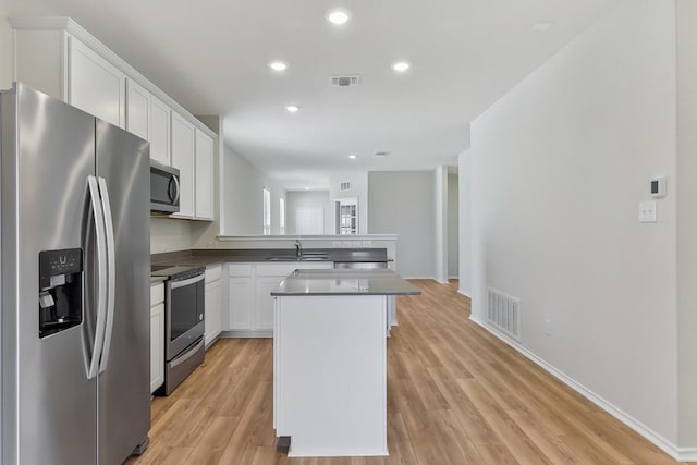 kitchen featuring a peninsula, visible vents, stainless steel appliances, and a sink