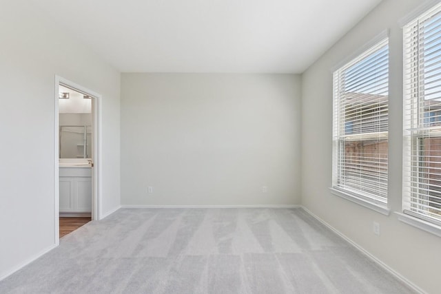 spare room with baseboards and light colored carpet