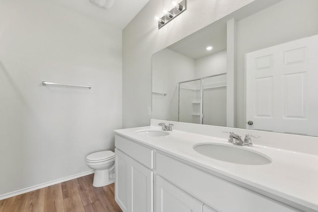 full bath with a shower with door, a sink, toilet, and wood finished floors