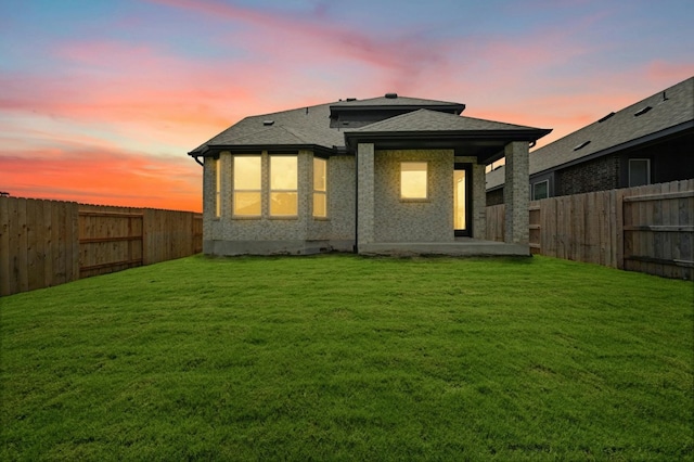 back house at dusk featuring a yard