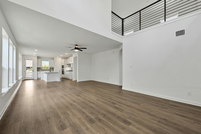 unfurnished living room featuring ceiling fan, dark hardwood / wood-style floors, and sink