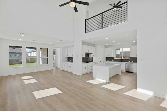 interior space featuring a high ceiling, light wood-type flooring, ceiling fan, and sink