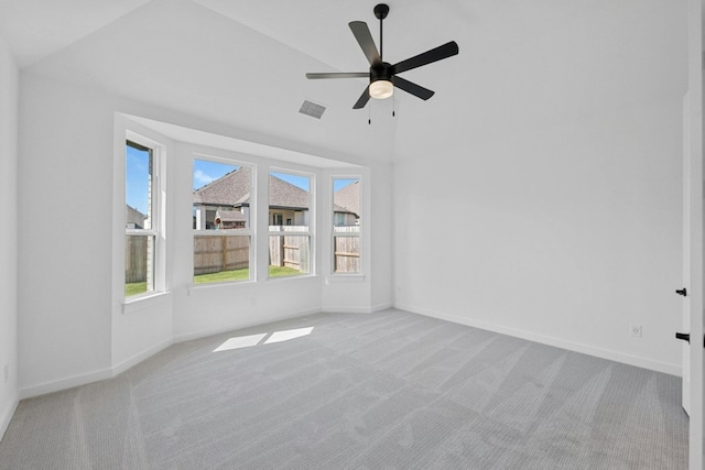 unfurnished room featuring ceiling fan, lofted ceiling, a wealth of natural light, and light colored carpet